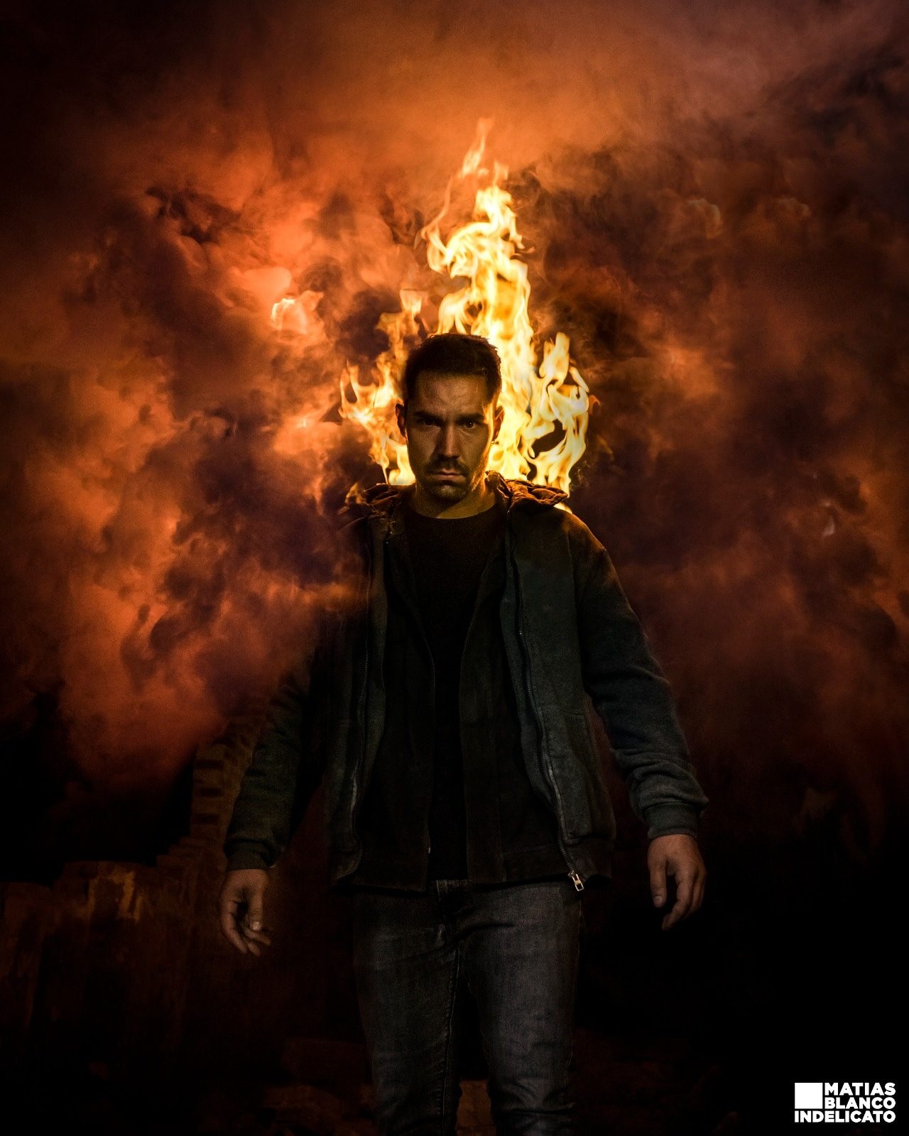 Actor caminando ante un muro de fuego